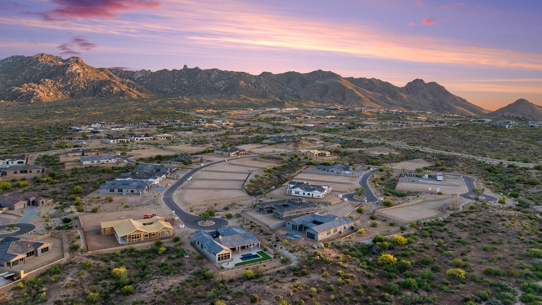 Desert foothills under a pink dusk sky, from the air
