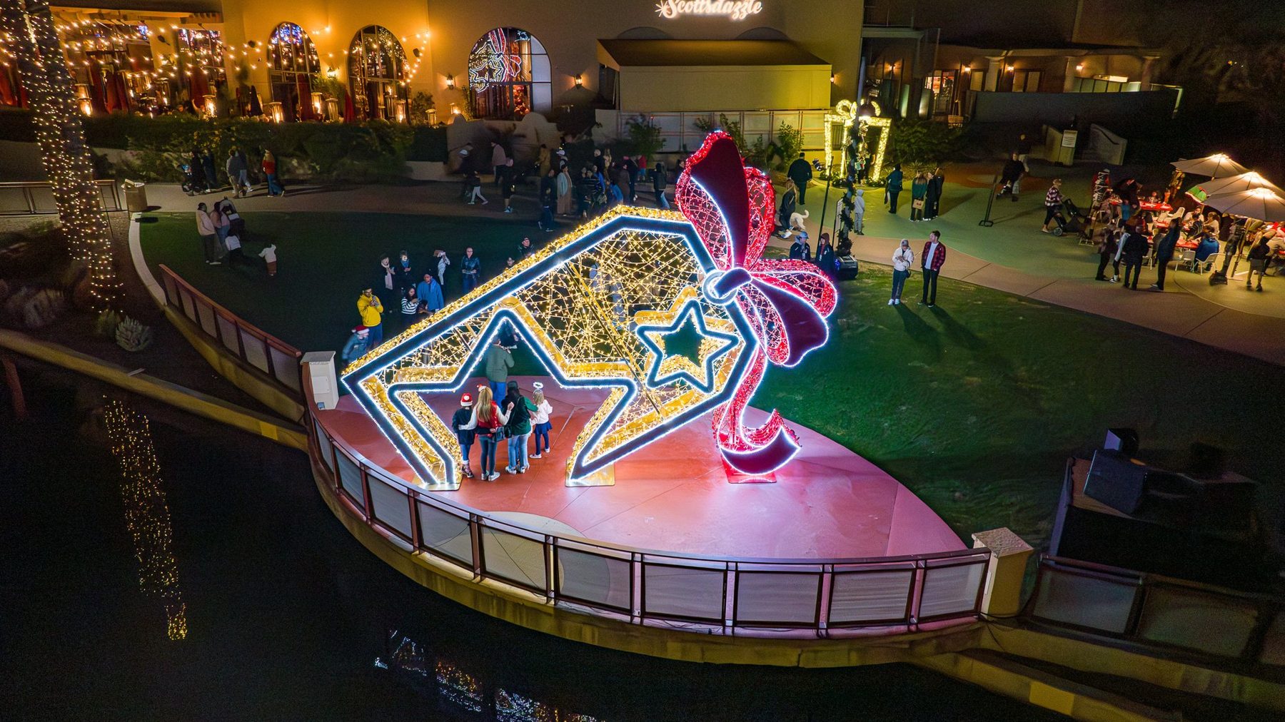 A lit stage and sculptures along the canal at night, from the air
