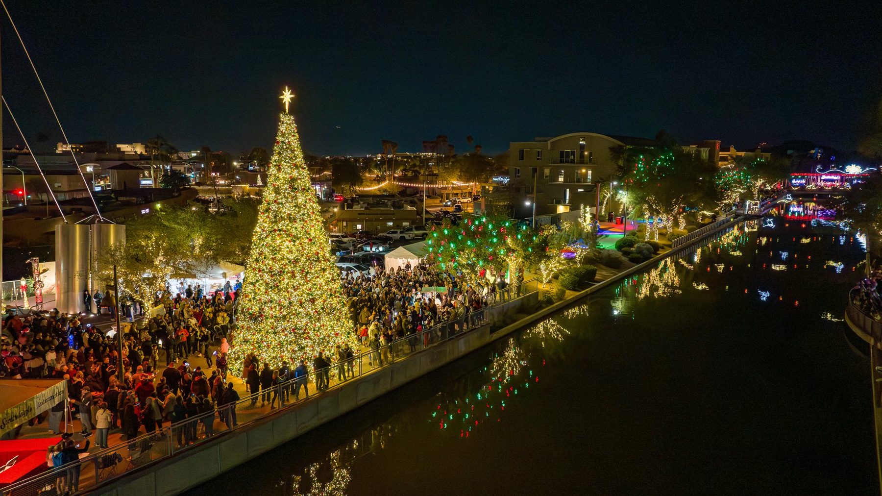 A lit tree and crowds along the Scottsdale canal, from the air